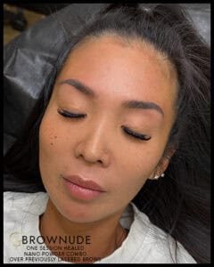 Close-up of a woman with freshly tattooed eyebrows and closed eyes.
